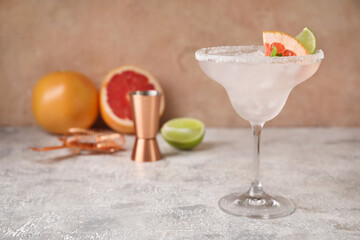 Glass of tasty grapefruit margarita on light background