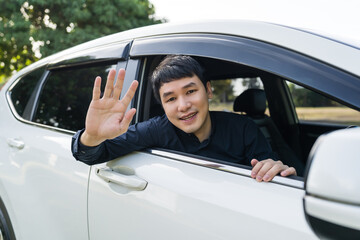 man open window of a car and raising his hand