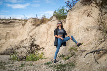 caucasian female model poses in sand quarry with blue sky, in summer sunny day