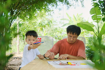 Home – based Learning (HBL), Parent sitting homeschooling with little kid, Asian Father and son...