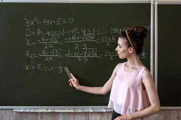 Clever female student writing on a chalkboard completing mathematical formulas