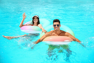 Young couple with inflatable rings in swimming pool