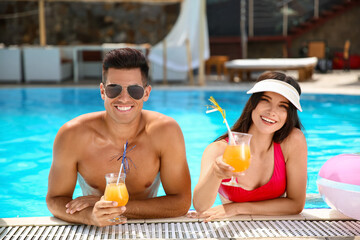 Young couple with cocktails in swimming pool