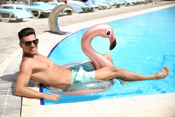 Young man with inflatable ring in swimming pool
