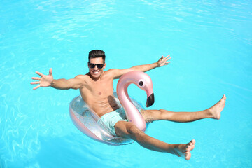 Young man with inflatable ring in swimming pool