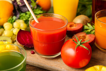 Glasses with healthy juice, fruits and vegetables on color wooden background, closeup