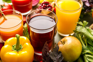 Glasses with healthy juice, fruits and vegetables on color wooden background