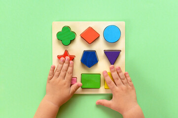 The child collects a multicolored wooden sorter. Educational logic toy for kid's