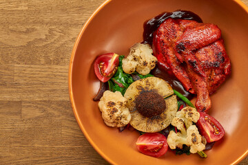 Fried chicken in Indian spices, with pineapple, broccoli and cherry tomatoes in a plate on a wooden background. With noise grain