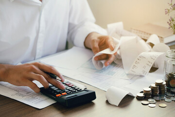 Man calculate domestic bills at home. Man using a calculator checking balance and costs at modern...