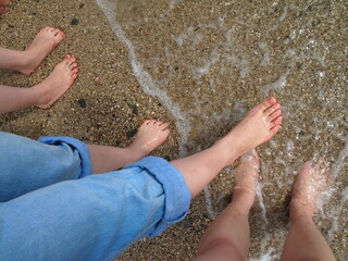 波打ち際に立つ三人の足　