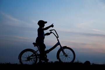 Fototapeta na wymiar silhouette of a boy on a bicycle in nature