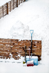 Different snow shovels or pushers standing on the fence, snowy background