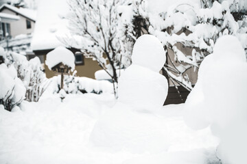 Fototapeta na wymiar Snowman standing in the garden, snow covered on winter season