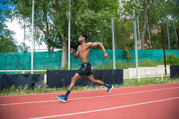 African American muscular young man running on running track