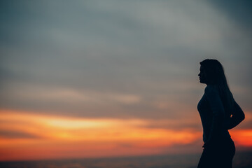 Young woman silhouette on the seashore pebble beach