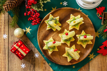 Festive snack of canapes on the Christmas table. Fruit canapes with cheese, kiwi and pineapple. Top view flat lay background. - obrazy, fototapety, plakaty