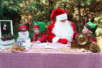 Santa Claus and little elves sort through mail, read letters from children. House, workshop of Santa Claus. Christmas and New Year