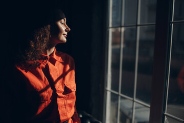 Young brunette curly woman in orange suit. Female in colorful overalls portrait
