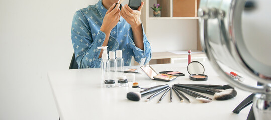 Professional Woman blogger vlogger is showing cosmetics products with recording video  makeup...
