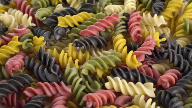 Multicolored raw Italian fusilli pasta. Close up. Rotating dry traditional macaroni