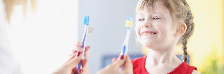 Little girl choosing toothbrush at dentist in clinic