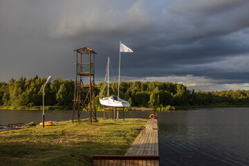 Boat on a pedestal. Cloudy sky over the river in the evening. Picturesque landscape with clouds and...