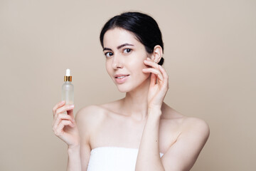 Woman holds hyaluronic serum. Photo of pretty woman with perfect skin on beige background. Beauty product presentation