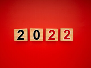 Happy New Year 2022 on wooden cubes isolated on a red background. The business growth process for goal. Christmas and Happy New year