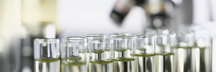 Many glass test tubes with yellow liquid standing in laboratory closeup