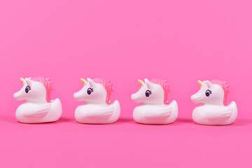 Four cute rubber duck unicorn in a row on pink background