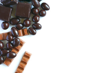 Square candies, chocolate bars and chocolate covered nuts on a white background. Place for your text. Cover for pastry courses.