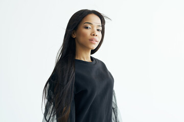 Fototapeta premium beautiful fashionable woman of african appearance dark shirt long hair light background