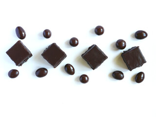Chocolate-covered cake and chocolate-covered nuts on a white plate. Copy space. Confectionery concept.
