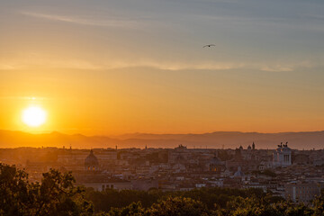 The sun is rising over the center of Rome full of ancient buildings and monuments