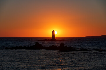 The Sun is setting down behind the Mangiabarche's Lighthouse in front of Carloforte, Island of San Pietro, and Calasetta, Sant'Antioco