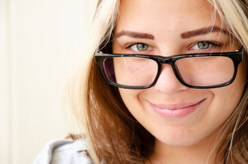 Brunette young woman with glasses. Concept of choosing profession. Beautiful caucasian young girl with green eyes looks at camera and smiles. Student, entrant or young employee.