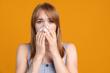 Portrait of young Caucasian girl has a cold isolated on yellow color studio background. Concept of human emotions, facial expression, health care, feelings, ad.