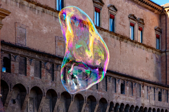 A large soap bubble by a street artist as it hangs in the air in Piazza Maggiore, Bologna, Italy