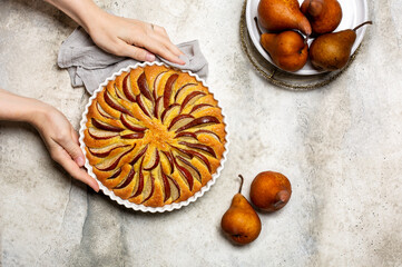 Woman's hand holding  just made pie with brown pears. Light background, copy space. Copy space.