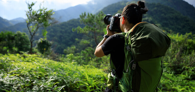 Woman photographer taking pictures in summer mountains