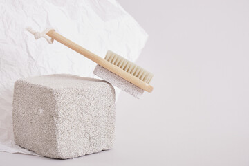wooden natural pedicure brush on a stone stand on a gray background, brush massage and skin cleansing concept
