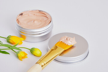 small beautiful flowers, makeup brush and cosmetic red clay in an aluminum jar, natural cosmetics
