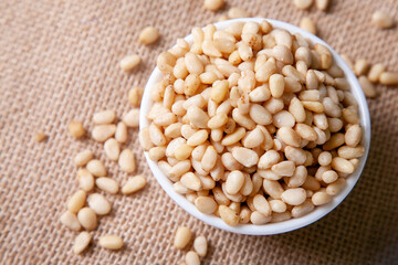 Organic Pine nuts in a bowl on a jute napkin top view flat lay