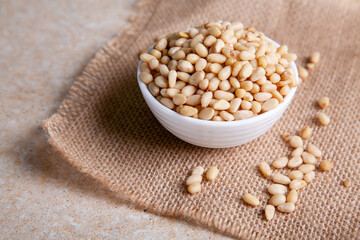 Organic Pine nuts in a bowl on a jute napkin