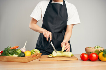 Woman in black apron cutting vegetables housework cooking