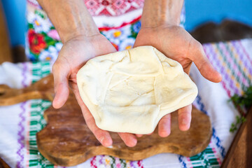 image with the hands of a lady cooking traditional Romanian fried pies with cheese in traditional clothes.