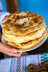 image with the hands of a lady cooking traditional Romanian fried pies with cheese in traditional clothes.