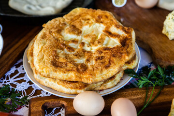 image with the hands of a lady cooking traditional Romanian fried pies with cheese in traditional clothes.
