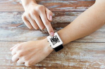 technology and health care concept - close up of woman's hands with qr code on smart watch